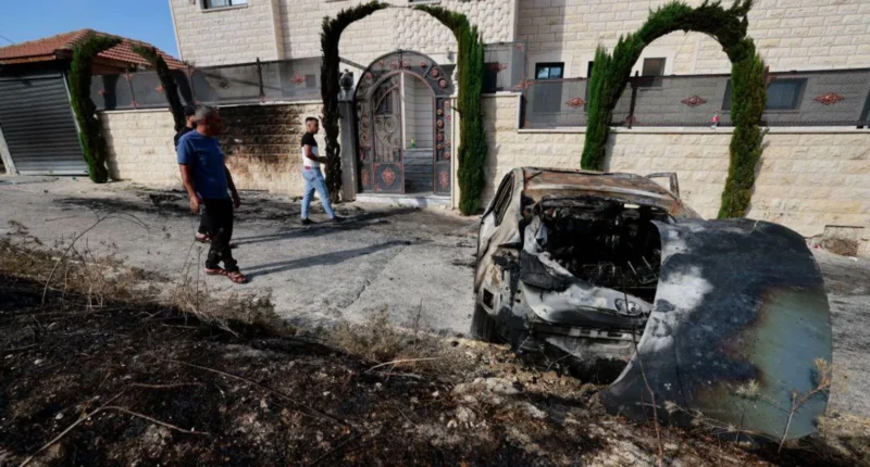 Palestinian residents assess the damage after Israeli settlers attacked the village of Jit